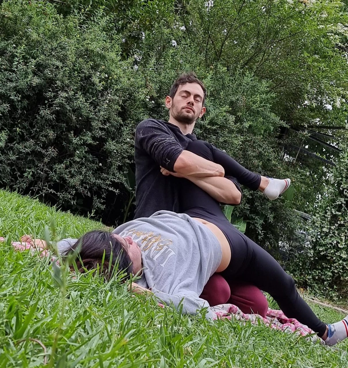 Federico stretching someone's leg. His eyes are closed as if he is meditating.